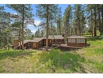 Stunning home exterior featuring natural wood siding, a deck, and lush greenery at 3251 Interlocken Dr, Evergreen, CO 80439
