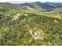 Panoramic aerial view of home on a wooded lot near a mountain with an detached garage at 9648 Yegge Rd, Morrison, CO 80465