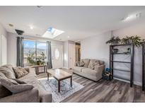 Inviting living room with two sofas, wood-look floors, skylight, and view of the mountains at 208 Wark Ave, Berthoud, CO 80513