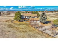 Sprawling two-story home with a stone facade, attached garage, mature trees, and ranch-style fencing around the property at 12925 Sierra Cir, Parker, CO 80138
