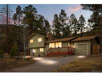 Inviting two-story home featuring a charming front porch and attached garage nestled among tall pine trees at 31219 Florence Rd, Conifer, CO 80433