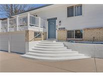Charming two-story home with a blue door, painted white brick accents, and a welcoming front porch at 4090 S Tamarac Dr, Denver, CO 80237