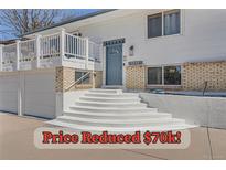 Inviting home featuring a blue front door, brick accents, and a welcoming white staircase at 4090 S Tamarac Dr, Denver, CO 80237