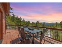 Outdoor deck features a dining table set with views of mountain and sunset at 27100 Molly Dr, Conifer, CO 80433