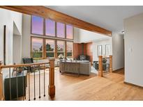 Inviting living room featuring a wood-burning stove, exposed beam, and large windows showcasing a scenic view at 27100 Molly Dr, Conifer, CO 80433