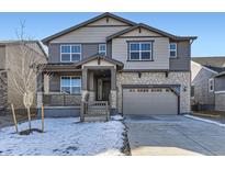 Charming two-story home featuring stone accents, a covered porch, and a gray two-car garage at 24734 E Pacific Pl, Aurora, CO 80018