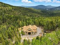 Stunning aerial view of home nestled in lush forest with mountain views in the background at 30041 Marys Dr, Conifer, CO 80433