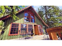 Charming cabin featuring a spacious deck, large windows, and wooded surroundings at 573 97 Cir, Breckenridge, CO 80424