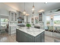 A spacious kitchen features a center island, pendant lighting, stainless steel appliances, and light colored cabinets at 3488 Dawson Rd, Sedalia, CO 80135
