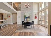Bright dining room features soaring ceilings, exposed brick wall, chandelier, and large windows with plenty of natural light at 5149 E Links Cir, Centennial, CO 80122