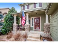 Inviting front porch with stone accents and stately columns, displaying the American flag at 9882 S Hoyt Ct, Littleton, CO 80127