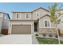 Charming two-story tan home featuring a two-car garage, manicured front yard, and stone accents at 6428 Vista Cliff Loop, Castle Rock, CO 80104