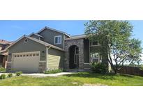 Charming home with stone accents, well-manicured lawn and two-car garage on a sunny day at 21580 Longs Peak Ln, Parker, CO 80138