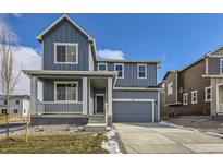 Charming two-story home featuring a covered porch, gray siding, and a two-car garage at 735 Sunflower Dr, Brighton, CO 80601