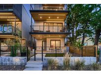 Modern three-story home with multiple balconies, a fenced yard, and contemporary design elements at 3232 W 16 Ave, Denver, CO 80204