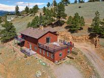 Beautiful home exterior with a large deck, overlooking lush greenery and mountain views at 24170 Matterhorn Dr, Indian Hills, CO 80454