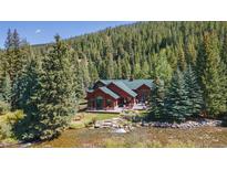 Beautiful exterior view of the red home surrounded by pine trees and flowing river at 189 Ginger Quill Ln, Breckenridge, CO 80424