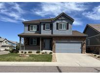 Two-story home with stone accents, gray siding, covered porch, and well-maintained landscaping at 13903 Hillsboro Dr, Parker, CO 80134