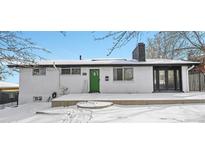 White brick ranch home with green door, snow covered yard at 9040 Yucca Way, Thornton, CO 80229