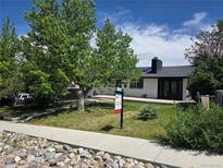 Charming single-story home featuring a manicured front yard, lush landscaping and a 'For Sale' sign at 9040 Yucca Way, Thornton, CO 80229