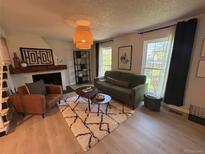 Bright living room features stylish decor, a cozy fireplace, and natural light from the windows at 9424 E Girard Ave, Denver, CO 80231