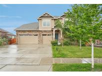 Charming two-story home with a stone and tan siding, three-car garage, and a well-maintained lawn at 594 Fall River Ct, Brighton, CO 80601