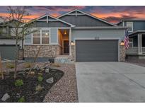 Charming home with stone accents, a two-car garage, and professional landscaping set against a colorful sky at dusk at 3844 Sandy Vista Ln, Castle Rock, CO 80104