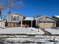 Charming home featuring a two-car garage and well-maintained front yard covered in snow at 1962 S Ivory Way, Aurora, CO 80013