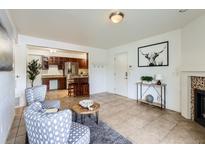 Inviting living room with tile flooring, opening to the kitchen with bar stool seating and stainless steel refrigerator at 10251 W 44Th Ave # 8-102, Wheat Ridge, CO 80033