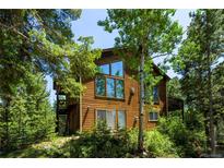 Attractive wood home featuring large windows and wooded surroundings, offering a serene mountain living experience at 11526 Green Cir, Conifer, CO 80433