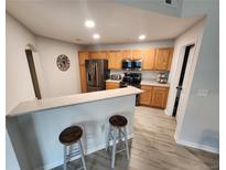 Bright kitchen features stainless steel appliances, wood cabinetry, and a breakfast bar with stool seating at 5755 N Genoa Way # 14-105, Aurora, CO 80019