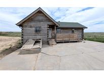 Rustic log cabin home featuring a concrete patio and traditional design elements at 11897 Roxburg St, Strasburg, CO 80136