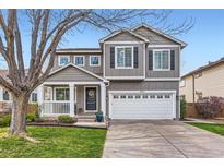 Charming two-story home with a well-maintained lawn, gray siding, white trim, covered porch, and attached two-car garage at 9879 Sydney Ln, Highlands Ranch, CO 80130