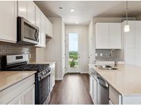 Modern kitchen featuring white cabinets, stainless steel appliances, and a stylish tile backsplash at 457 Interlocken Blvd # 105, Broomfield, CO 80021