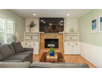 Inviting living room featuring a cozy brick fireplace, built-in shelving, and a comfortable gray sofa at 7169 S Grape Ln, Centennial, CO 80122