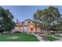 Elegant home featuring a red front door, manicured lawn, and mature trees, creating a welcoming entrance at 5080 Barn Swallow Way, Parker, CO 80134