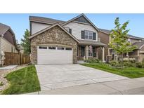 Charming two-story home featuring stone accents, a two-car garage, and a well-manicured lawn at 853 Jenny Ln, Berthoud, CO 80513