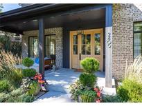 Inviting covered front entry featuring light brick, wood doors, and curated plantings at 2409 S Fillmore St, Denver, CO 80210