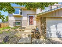 Inviting front entrance with a red door, light brick accents and rock landscaping at 3235 S Newland St, Denver, CO 80227