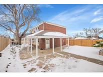 Brick home with covered patio, flagstone patio, and fenced backyard in winter at 3560 N Adams St, Denver, CO 80205