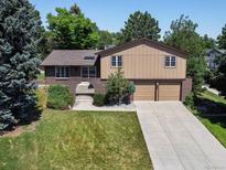 Two-story home featuring a brick and wood exterior, mature trees, and an inviting front yard with large driveway at 8893 W Harvard Dr, Lakewood, CO 80227