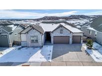 Beautiful single-Gathering home with a three-car garage, stone accents, and a snow-dusted roof against a scenic mountain backdrop at 6066 Leilani Dr, Castle Rock, CO 80108