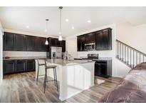 Beautiful kitchen features dark cabinetry, a spacious island with seating, granite countertops, and stainless steel appliances at 5710 Eagle River Pl, Brighton, CO 80601