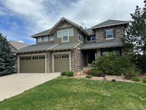Two-story home featuring a three-car garage, stone accents, and manicured lawn at 26764 E Canyon Ave, Aurora, CO 80016