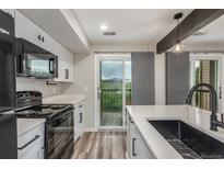 Bright kitchen with modern appliances, white cabinetry, and a sliding glass door to balcony at 4899 S Dudley St # 14F, Littleton, CO 80123
