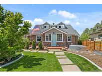 Charming stone home with blue door, dormer windows, American flag, and a well-manicured lawn at 895 Nile Ct, Golden, CO 80401