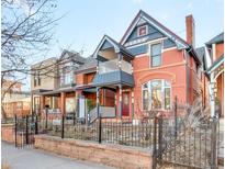 Charming two-story brick home with a front yard, black iron fence, and colorful details on the facade at 3349 Bryant St, Denver, CO 80211
