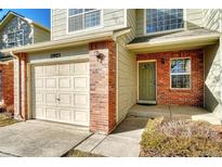 Charming townhouse exterior with brick accents, a two-car garage and a well-maintained front yard at 15925 E 13Th Ave, Aurora, CO 80011