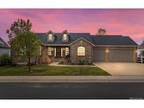 Charming brick home with a well-manicured lawn, dormer windows, and a three-car garage at 5708 Wetland Loop, Frederick, CO 80504