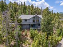 Beautiful mountain home with large windows and a wraparound deck surrounded by lush forest at 6882 Snowshoe Trl, Evergreen, CO 80439